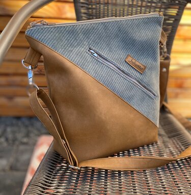 Braun-graue Umhängetasche mit diagonalem Cord-Einsatz, Außenreißverschluss und verstellbarem Schulterriemen.