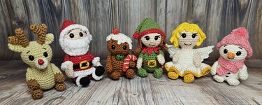 Sechs gehäkelte Amigurumi-Weihnachtsfiguren auf Holzoptik: Rentier, Weihnachtsmann, Lebkuchenmann, Wichtel, Engel und Schneemann.