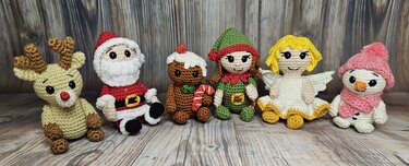 Gehäkelte Amigurumi-Weihnachtsfiguren: Rentier, Weihnachtsmann, Lebkuchenmännchen, Elf, Engel und Schneemann nebeneinander
