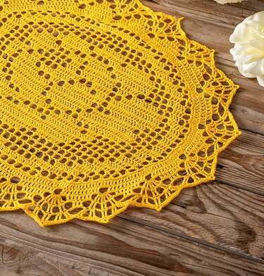 Rundes gelbes gehäkeltes Deckchen mit Spitzenrand auf Holzoberfläche