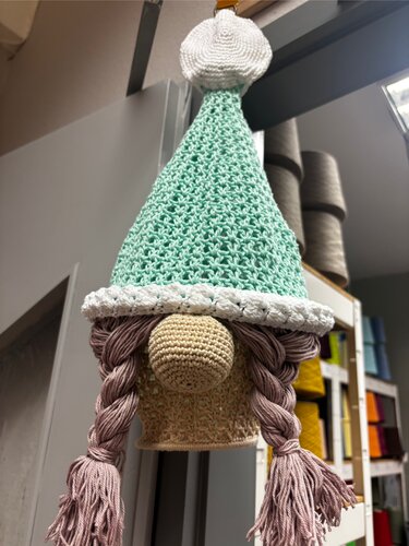 Handgehäkelter Wichtel mit mintgrüner Zipfelmütze, weißem Bommel, beiger Nase und langen rosa Zöpfen.