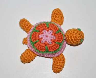 Gehäkelte Amigurumi-Schildkröte orange rosa mit Blumenpanzer