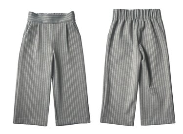 Vorder- und Rückansicht einer grauen Kinderhose mit weißen Nadelstreifen, weitem verkürztem Bein, Seitentaschen und elastischem Rückenbund.