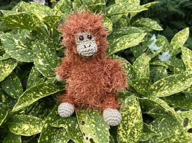 Nahaufnahme eines braunen flauschigen Amigurumi mit sichtbarer Maschenstruktur und beiger Schnauze