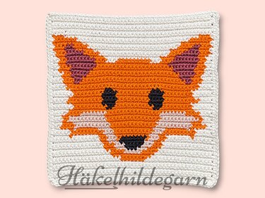 Gehäkeltes quadratisches Pixelmotiv mit orange-weißem Fuchskopf