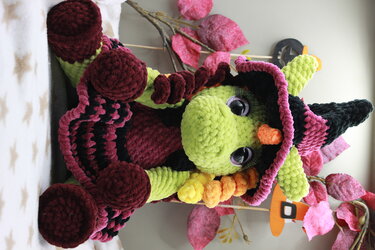 Gehäkelte grüne Amigurumi‑Hexe mit schwarzem Spitzhut, oranger Nase und flauschigem Garn