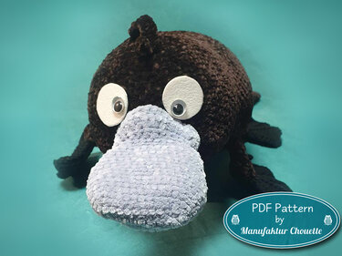 Gehäkeltes Schnabeltier-Amigurumi mit dunkelbraunem Körper und hellgrauem Schnabel vor türkisfarbenem Hintergrund.