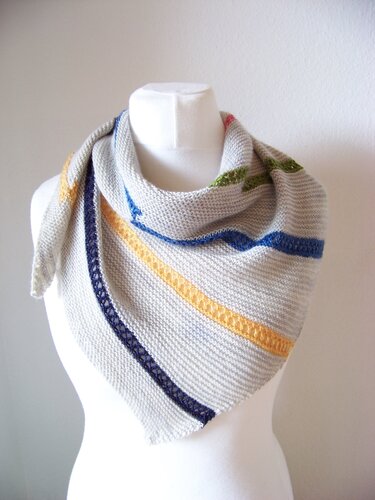 Hellgraues gestricktes Dreieckstuch mit kraus-rechts-Muster, Lochreihe und diagonalen blauen, gelben und grünen Streifen auf einer Schaufensterpuppe