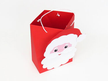 Rote Geschenktasche mit aufgesetztem Weihnachtsmanngesicht und gedrehter weißer Kordel