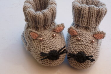 Paar gestrickter hellgrauer Babyschuhe in Mausform mit rosa Ohren, Perlenaugen und schwarzer Nase
