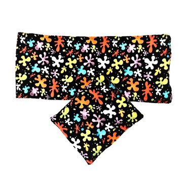 Zwei schwarze Stoffzuschnitte mit buntem Klecksmuster, ein längliches und ein quadratisches Stück