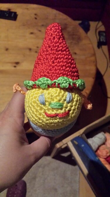 Handgehäkelter Amigurumi-Wichtel mit roter Zipfelmütze und gelbem Kopf