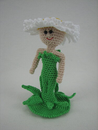 Gehäkelte Amigurumi-Puppe im Gänseblümchen-Design mit weißem Blütenhut und grünem Kleid.