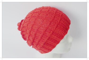 Korallfarbene gestrickte Schlupfmütze mit Kästchenmuster auf weißer Schaufensterpuppe, Seitenansicht