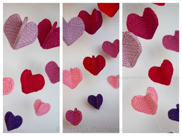 Handgehäkelte Herzen in Rosa, Rot und Lila als Girlande aufgehängt.