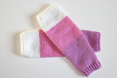 Gehäkelte Beinstulpen in Weiß, Rosa und Flieder nebeneinander gelegt
