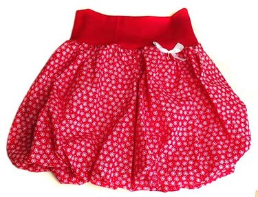 Roter Kinder-Pumprock mit dichtem weißen Blütenmuster und weißer Schleife am Bund