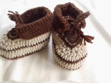 Zwei gehäkelte Babyschuhe mit braunen und beigen Streifen auf hellem Hintergrund