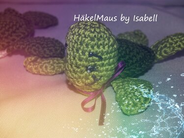 Gehäkelte grüne Amigurumi-Schildkröte mit lila Schleife