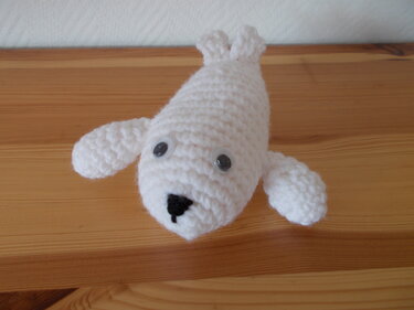 Weißes gehäkeltes Robben-Amigurumi mit Flossen und schwarzer Nase