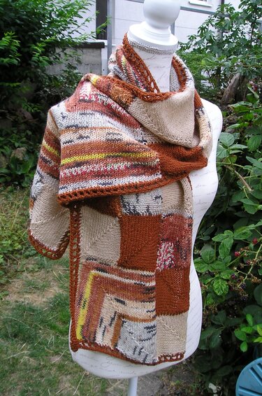 Gestrickter Patchwork-Schal in Braun-, Beige- und Gelbtönen auf Schneiderpuppe.