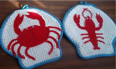 Crochet potholders with red crab and lobster designs and blue edging