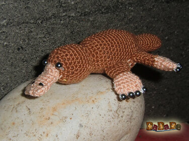 Gehäkeltes kleines Schnabeltier-Amigurumi in Braun und Beige mit Perlenaugen