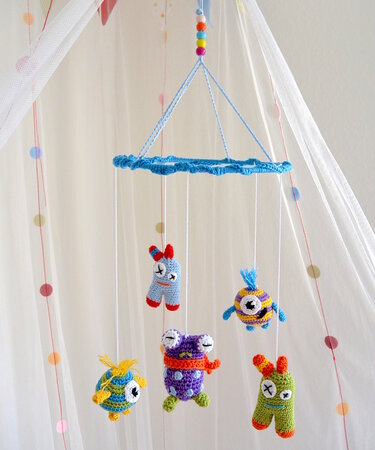 Gehäkeltes Mobile mit bunten Amigurumi-Figuren an blauem Ring und Perlen