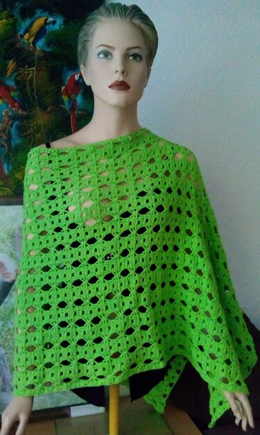 Grüner Damen-Poncho mit offenem Häkelmuster auf Puppe drapiert