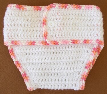 weiße gehäkelte Baby-Windelhose mit rosa-orangem Rand und Knopf