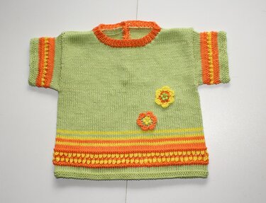 Kurzärmeliger gestrickter Baby-Kinderpullover hellgrün mit orange-gelben Streifen und zwei gehäkelten Blumen