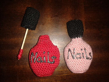 Gehäkelte rote und rosa Nagellackflaschen mit gehäkeltem Pinsel auf Holz