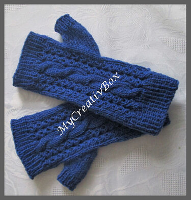 Dunkelblaue gestrickte Armstulpen mit Zopfmuster und Daumenloch, flach liegend.