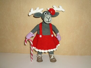 Gehäkeltes Rentier-Amigurumi mit weißem Geweih, rotem Kleid, lila Fäustlingen und Zuckerstange