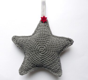 Gehäkelter grauer Sternanhänger mit Band und kleinem roten Zierstern