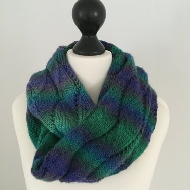 Mehrfarbiger Loop‑Schal mit Zopfmuster auf einer Schaufensterbüste