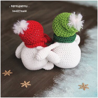 Rückansicht zweier gehäkelter Amigurumi‑Schneemänner mit roten und grünen Mützen, Arm in Arm