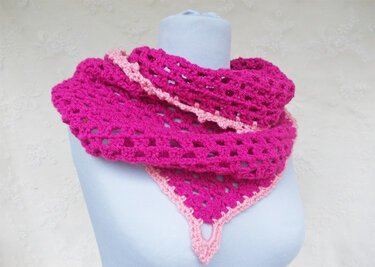 Pinkes gehäkeltes Dreieckstuch mit hellrosa Rand auf einer Schneiderpuppe