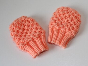 Paar gestrickter Baby-Fäustlinge in Koralle mit Noppenmuster und gerippten Bündchen