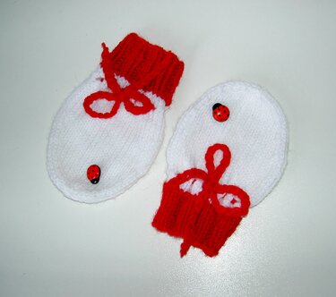 Weiß-rote gestrickte Babyfäustlinge mit roten Bündchen und Marienkäferknöpfen