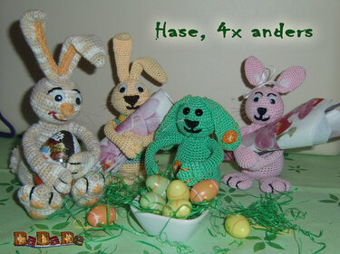 Vier pastellfarbene Amigurumi-Hasen um eine Schale mit Ostereiern und grünem Papiergras