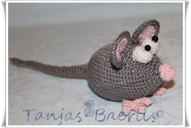 Kleine, schnell gehäkelte Amigurumi-Maus in Grau mit rosa Nase und Pfoten, Seitenansicht.