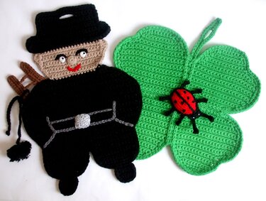 Gehäkelter Topflappen in Form eines vierblättrigen Kleeblatts mit Aufhängeschlaufe und ein gehäkelter Schornsteinfeger mit Leiter