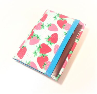Stoffhülle mit roten und rosa Erdbeeren und blauem Gummiband, geeignet für Reisepass oder als kleines Portemonnaie