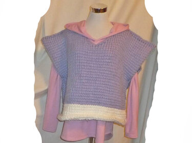 Ärmelloser, lilafarbener gehäkelter Pullunder mit V-Ausschnitt und cremefarbigem Saum über rosa Langarmshirt.