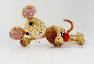 Beige gehäkelte Amigurumi-Maus mit rosa Ohreninnen und kleinem rotem Marienkäfer