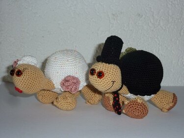 Zwei gehäkelte Schildkröten als Brautpaar, Braut mit weißer Schale und Schleier, Bräutigam mit schwarzem Panzer und Zylinder.