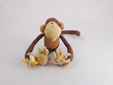 gehäkelter Amigurumi-Affe in Braun und Beige, sitzt mit Banane