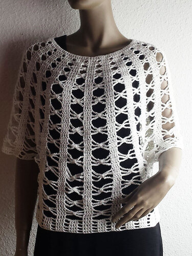 Weißes gehäkeltes Damen-Shirt mit vertikalem Lochmuster über schwarzem Top auf Schaufensterpuppe