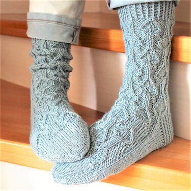 Nahaufnahme gestrickter Socken mit Zopfmuster und Rippenbündchen